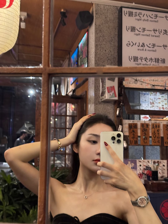 Bối cảnh những bức ảnh là khung cảnh Sài Gòn về đêm lung linh, rực rỡ. Mina Young tự tin tạo dáng bên bờ sông, phía sau là tòa nhà Landmark 81 nổi bật với ánh đèn vàng và tím, tạo nên một phông nền tuyệt đẹp.