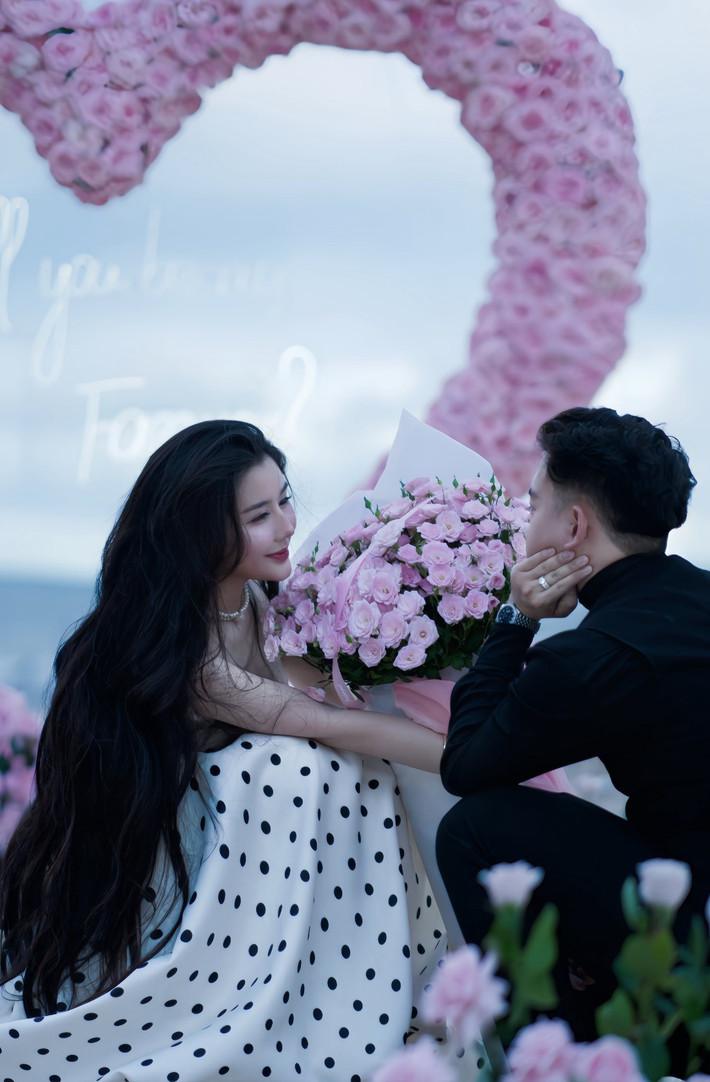 Không gian được trang hoàng bằng hàng nghìn đóa hồng pastel kết thành hình trái tim khổng lồ, cùng ánh nến lung linh và dòng chữ neon lãng mạn "Will you be my Forever?". (Ảnh: IGNV)