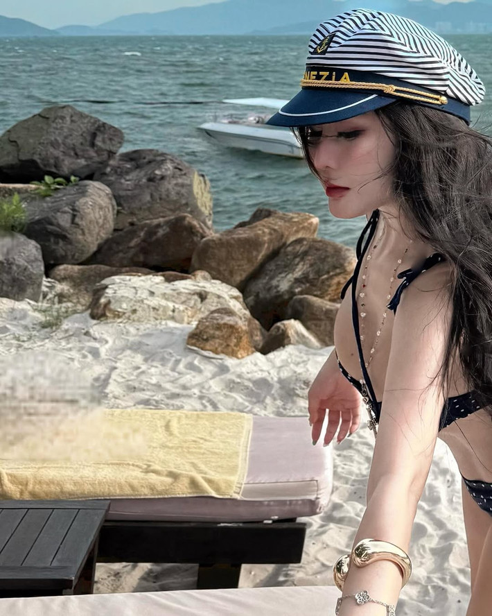 Cô nàng thả dáng bên bờ biển xanh biếc, mái tóc dài bồng bềnh tung bay trong gió, tạo nên khung cảnh vừa thơ mộng vừa đầy cuốn hút. Ánh nắng chan hòa càng làm tăng thêm vẻ đẹp rạng rỡ và làn da trắng mịn của cô.