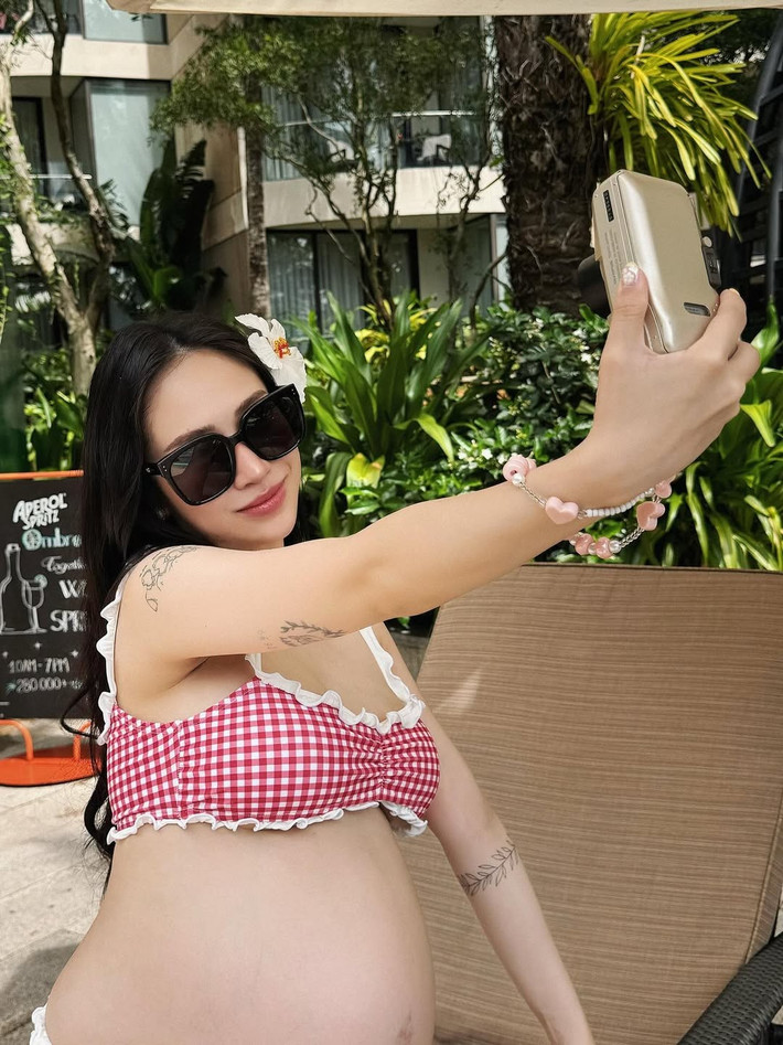 Cô không ngần ngại tạo dáng bên hồ bơi và khu vực quầy bar, thể hiện sự thoải mái và tận hưởng những khoảnh khắc cuối cùng của hành trình mang bầu.