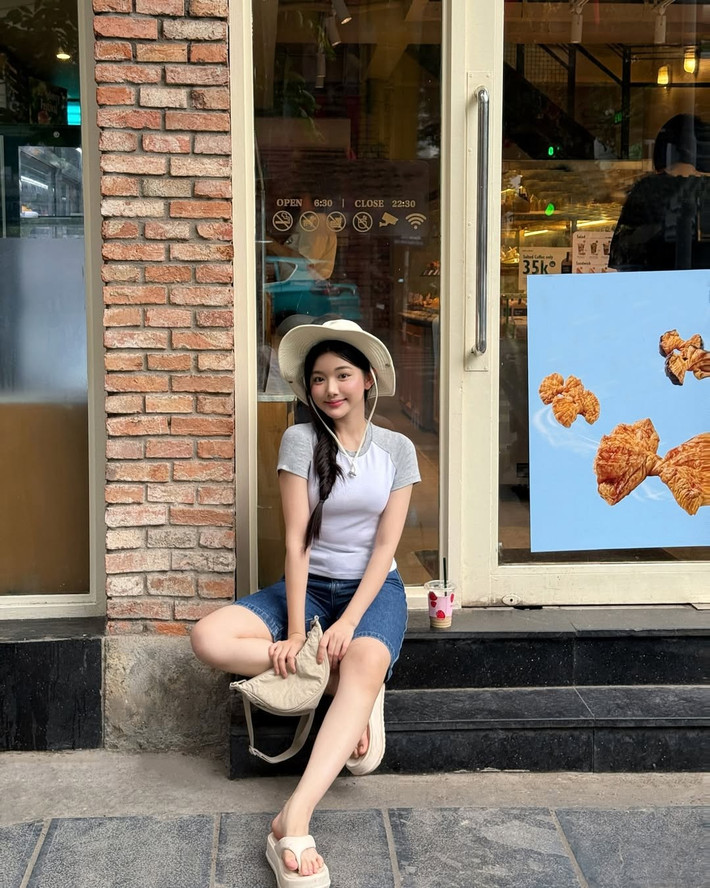 Tạo dáng trước tiệm bánh ngập ánh sáng vàng, tay cầm ly trà sữa, tóc tết lệch sang một bên, Quỳnh Trương không cố gắng tỏ ra "gợi cảm" hay "cool ngầu".
