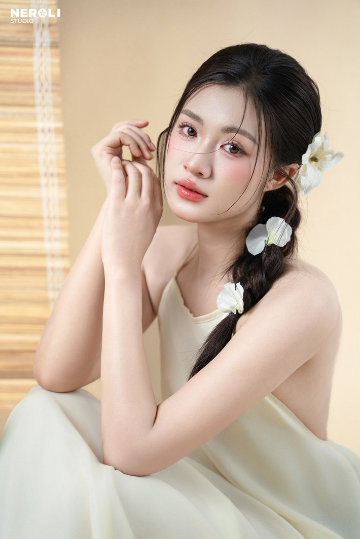Nét đẹp của Thu Hiền được khắc họa qua từng cử chỉ, ánh mắt. Cô nàng nhẹ nhàng ôm đóa sen trắng muốt, một biểu tượng của sự thanh khiết và cao quý, càng làm tăng thêm vẻ dịu dàng, e ấp.