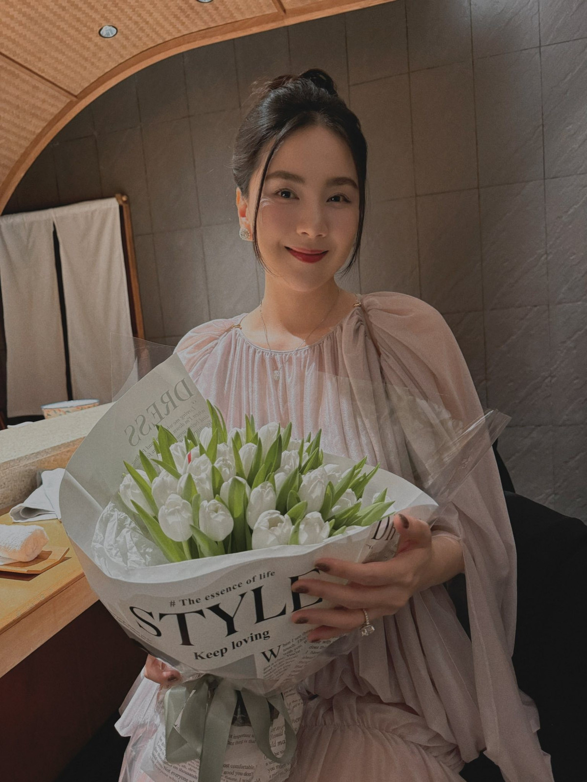 Xuất hiện trong ngày kỉ niệm, Mai Ngọc lựa chọn chiếc váy xếp ly dáng dài màu hồng pastel nhẹ nhàng với phần tay bồng điệu đà. Nhan sắc của "cô gái thời tiết" được nhận xét là ngày càng mặn mà, rạng rỡ, chuẩn phong thái phu nhân hào môn.