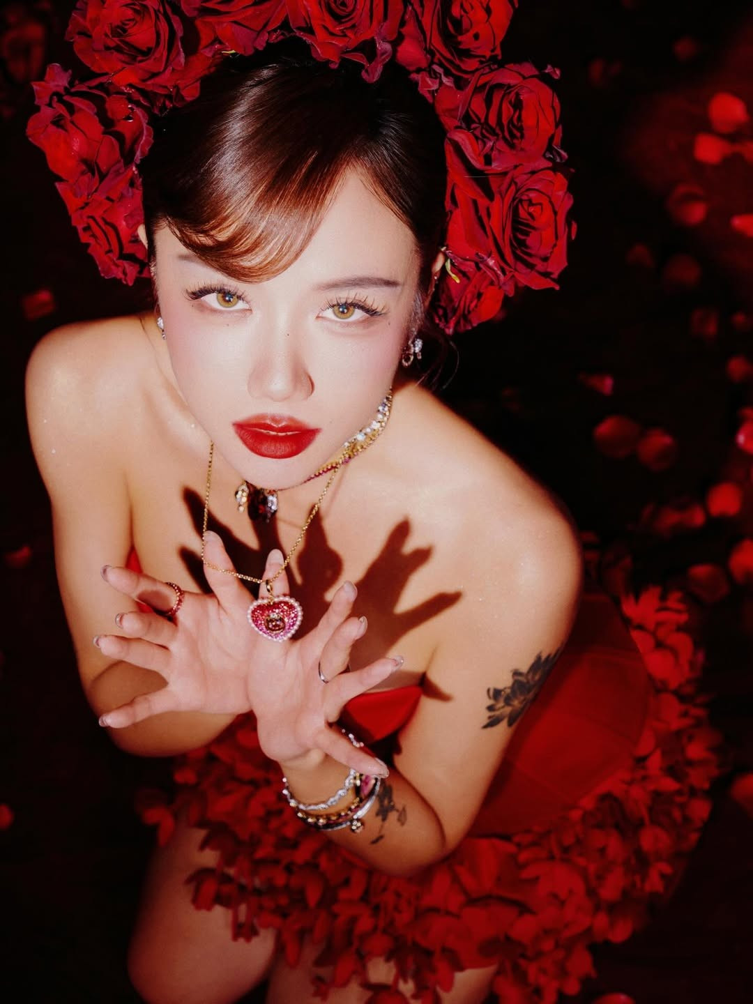 Nữ ca sĩ diện thiết kế váy quây bó sát với phần corset tôn vinh đường cong triệt để. Điểm nhấn là phần chân váy xòe rộng được kết từ hàng ngàn cánh hoa, tạo cảm giác như cô đang bước ra từ một đóa hồng nhung nở rộ. (Ảnh: IGNV)