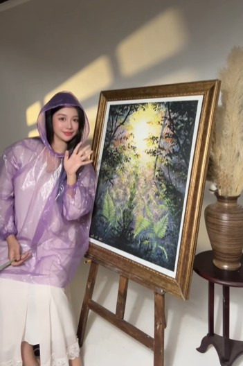 Thay vì chọn cách tranh cãi gay gắt hay im lặng, Minh Thư đã chọn một cách đáp trả cực kỳ thông minh và hài hước. Trong video mới nhất, cô xuất hiện với một chiếc áo mưa màu tím trùm kín từ đầu đến chân, che hoàn toàn vóc dáng bên trong. (Ảnh: FBNV)