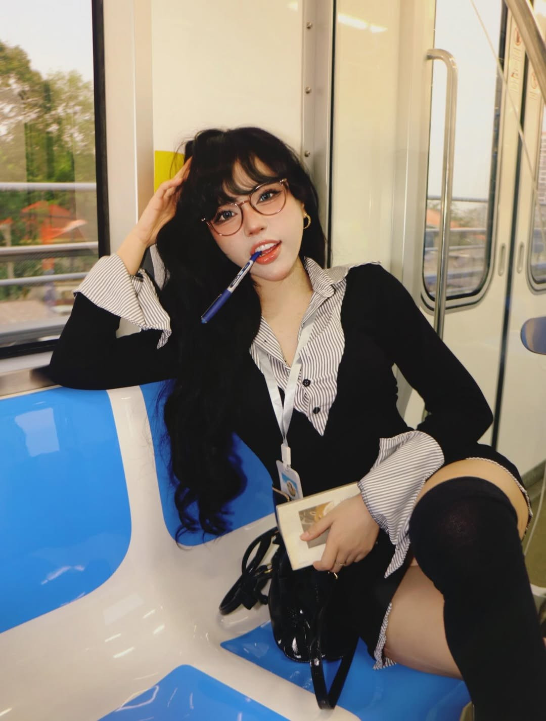 Dưới ánh đèn của toa tàu điện, nhan sắc của Bảo Khuyên Susan càng thêm nổi bật với làn da trắng không tì vết và lối trang điểm sắc sảo. Dù là biểu cảm tinh nghịch khi cầm bút, hay những lúc thả dáng tự nhiên trên ghế chờ, cô nàng vẫn giữ được thần thái "sang-xịn-mịn". (Ảnh: IGNV)