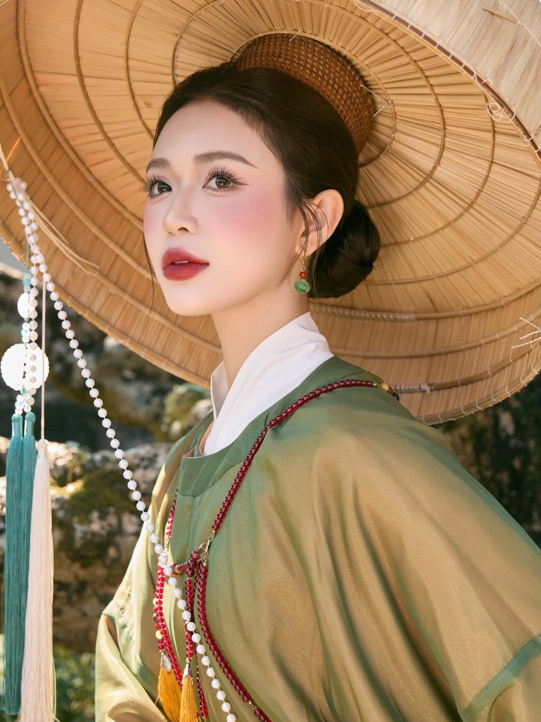 Những phụ kiện đi kèm như chuỗi hạt hồng ngọc đeo chéo thân áo, khuyên tai ngọc bích và chiếc quạt giấy đã hoàn thiện phong thái của một "nàng thơ cổ trang" bước ra từ tranh vẽ. (Ảnh: IGNV)