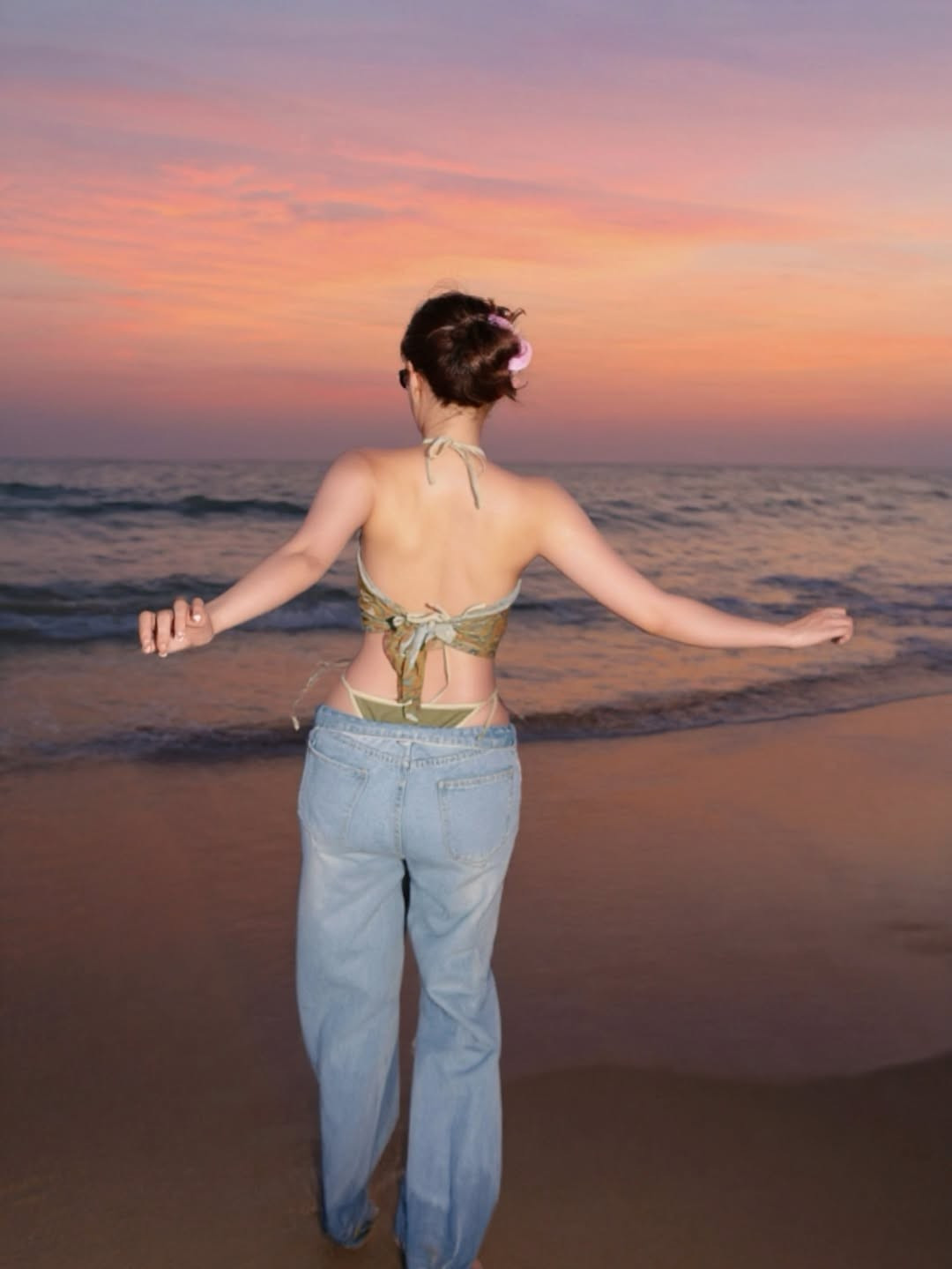 Cô nàng diện một chiếc áo yếm (halter top) crop-top họa tiết lạ mắt, khoe khéo vòng eo thon gọn và bờ vai trần gợi cảm. Dưới ánh hoàng hôn rực rỡ, bầu trời chuyển mình với những gam màu cam, hồng, tím hòa quyện, Kiều Trinh Xíu đã có những khoảnh khắc tạo dáng đầy thần thái.