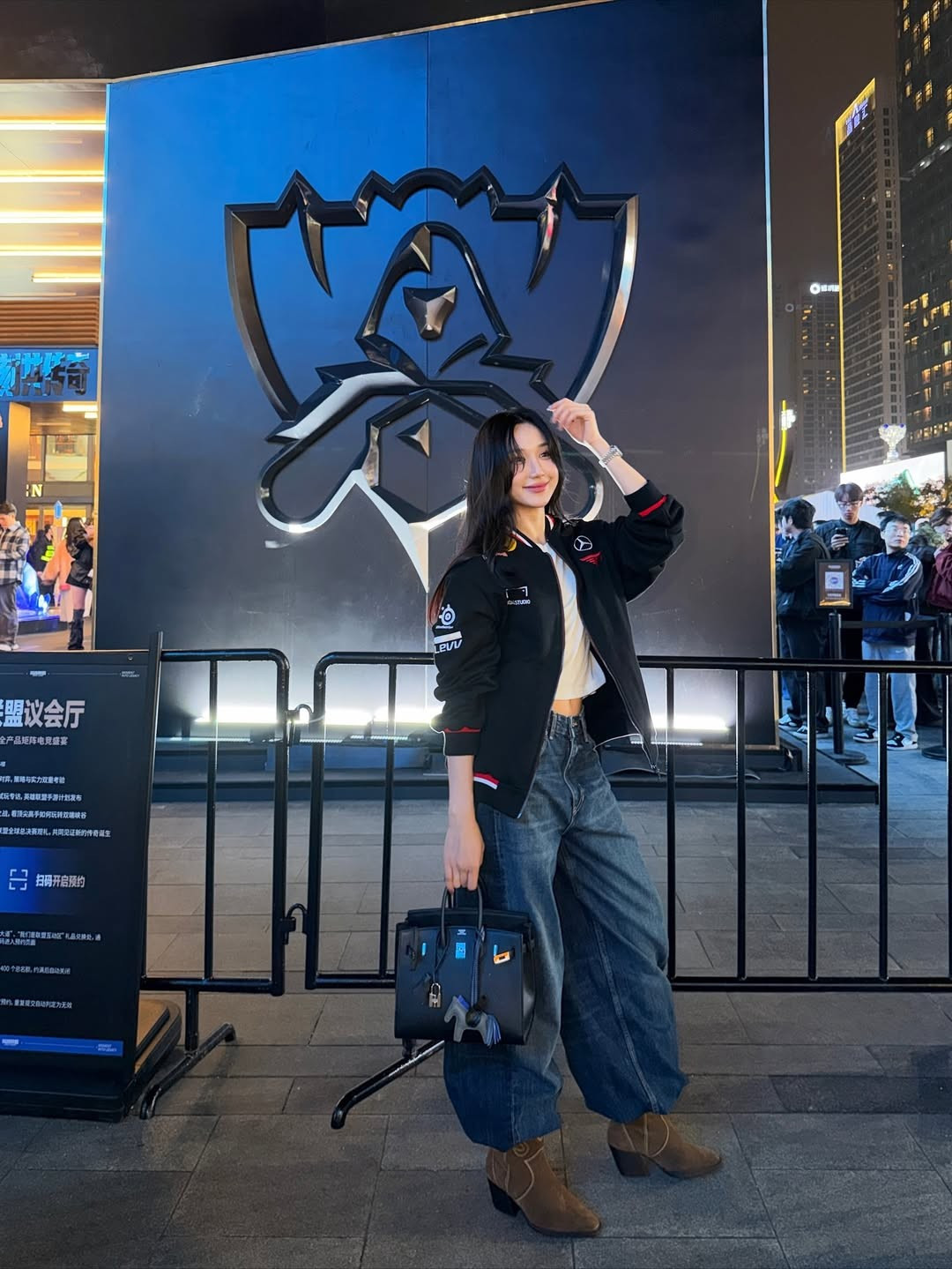 Cô nàng tranh thủ check-in ở phía ngoài nhà thi đấu, bên cạnh tấm bảng logo của bộ môn LMHT.