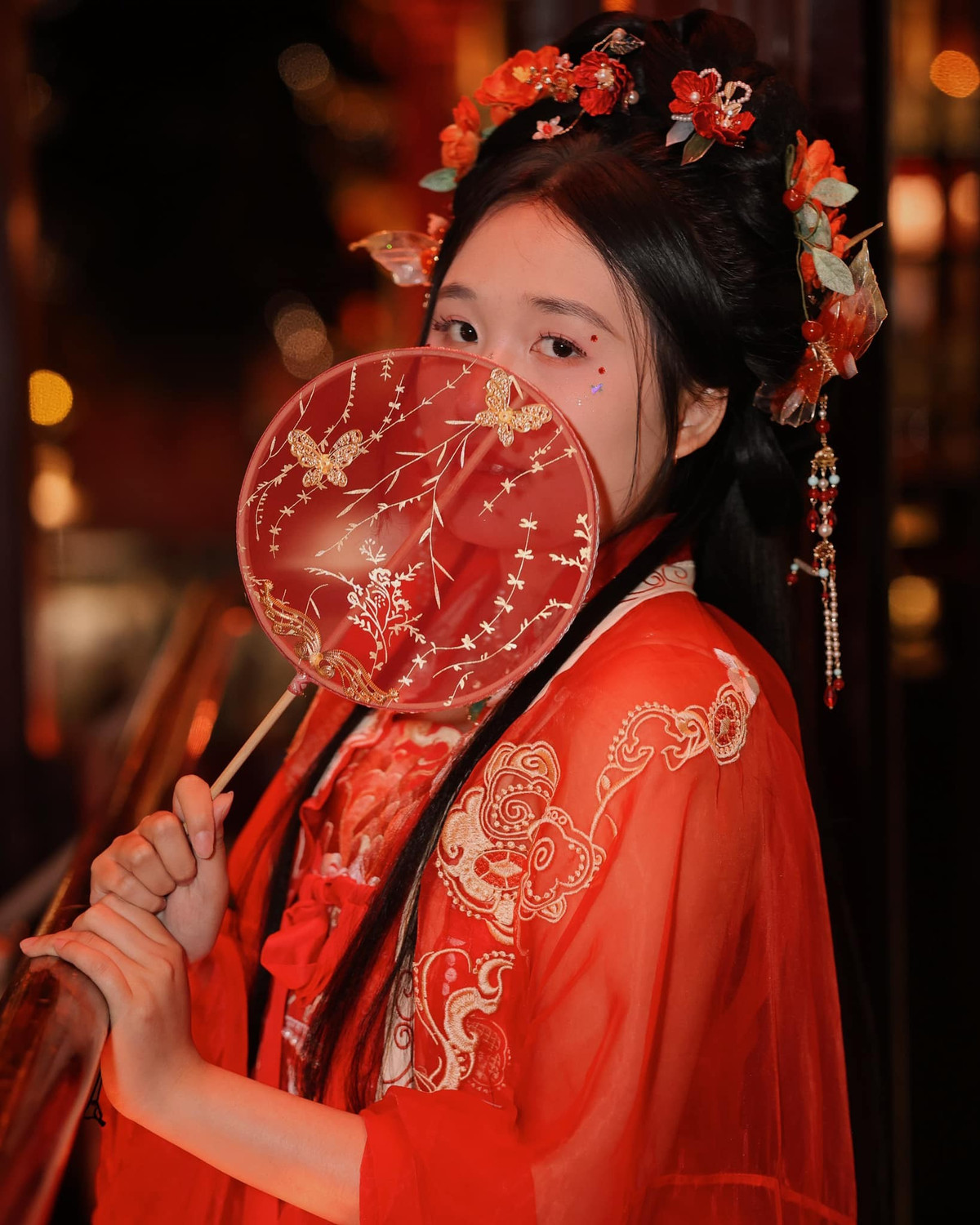 Mái tóc được búi cao cầu kỳ, điểm xuyết bằng hoa và trâm cài, cùng chiếc quạt tay trang trí tinh xảo – tất cả tạo nên một hình ảnh “tỷ tỷ xứ Trung” vô cùng duyên dáng và cổ điển.