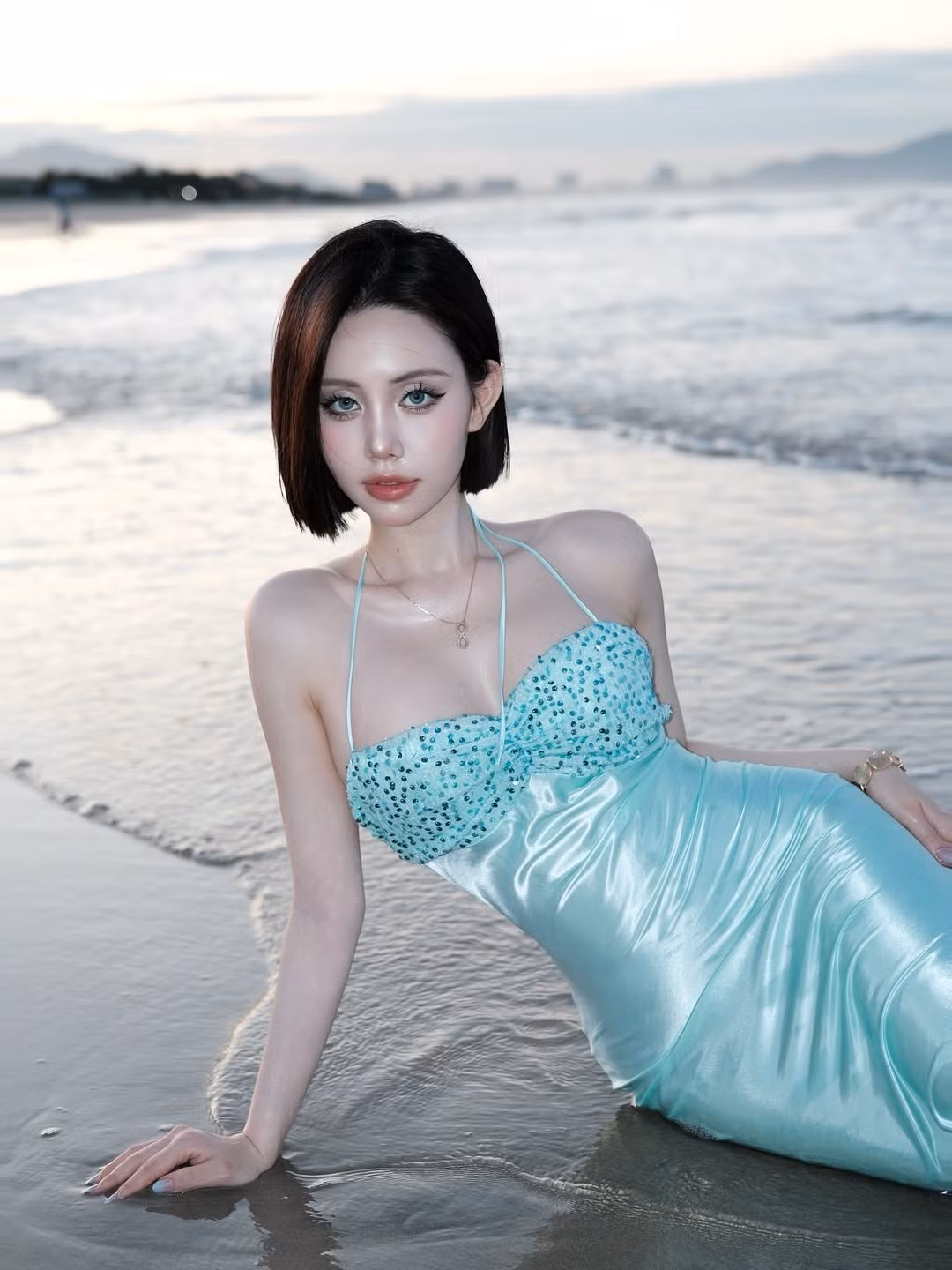 Chiếc váy khi ướt nước càng thêm phần quyến rũ, khoe trọn những đường cong mềm mại và vóc dáng đồng hồ cát. Mái tóc bob đen tuyền được tạo kiểu ướt nhẹ, kết hợp với lối trang điểm sắc sảo, đôi mắt to tròn cùng bờ môi căng mọng, đã giúp Thúy Quỳnh toát lên vẻ đẹp ma mị, đầy cuốn hút và thần thái của một nữ thần biển cả.