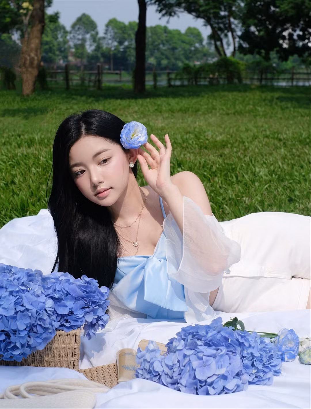 Cô khoác lên mình một chiếc áo croptop màu xanh da trời nhạt với điểm nhấn là chiếc nơ to bản, kết hợp cùng quần shorts trắng và áo khoác mỏng manh bên ngoài. Set đồ này không chỉ tôn lên vóc dáng mảnh mai mà còn rất phù hợp với concept dã ngoại. (Ảnh: IGNV)