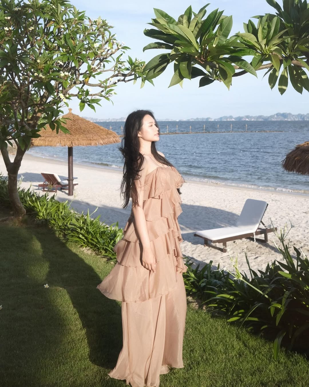 Cô nàng diện một chiếc váy maxi hai dây màu nâu đất với thiết kế xếp tầng bồng bềnh, tạo nên vẻ ngoài thướt tha và bay bổng.