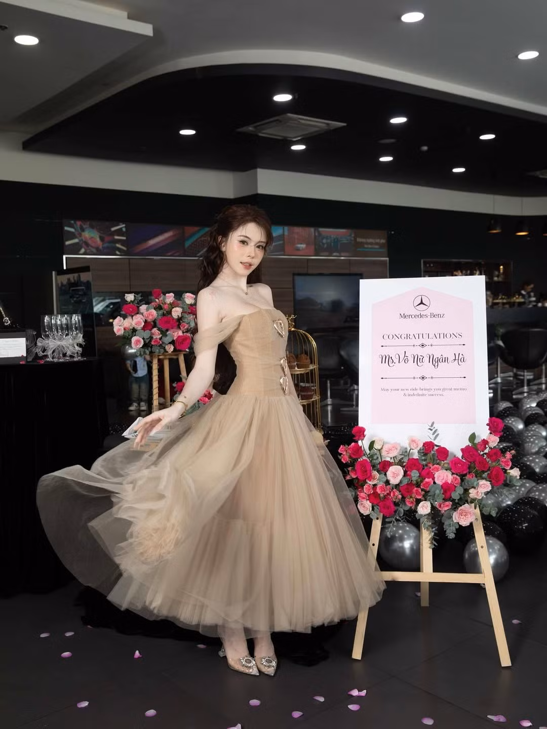 Ngân Hà tự tin tạo dáng bên chiếc Mercedes-Benz màu trắng, với bó hoa hồng đỏ rực và những quả bóng bay hình trái tim lấp lánh, tạo nên một khung cảnh chúc mừng đầy lãng mạn và sang trọng.