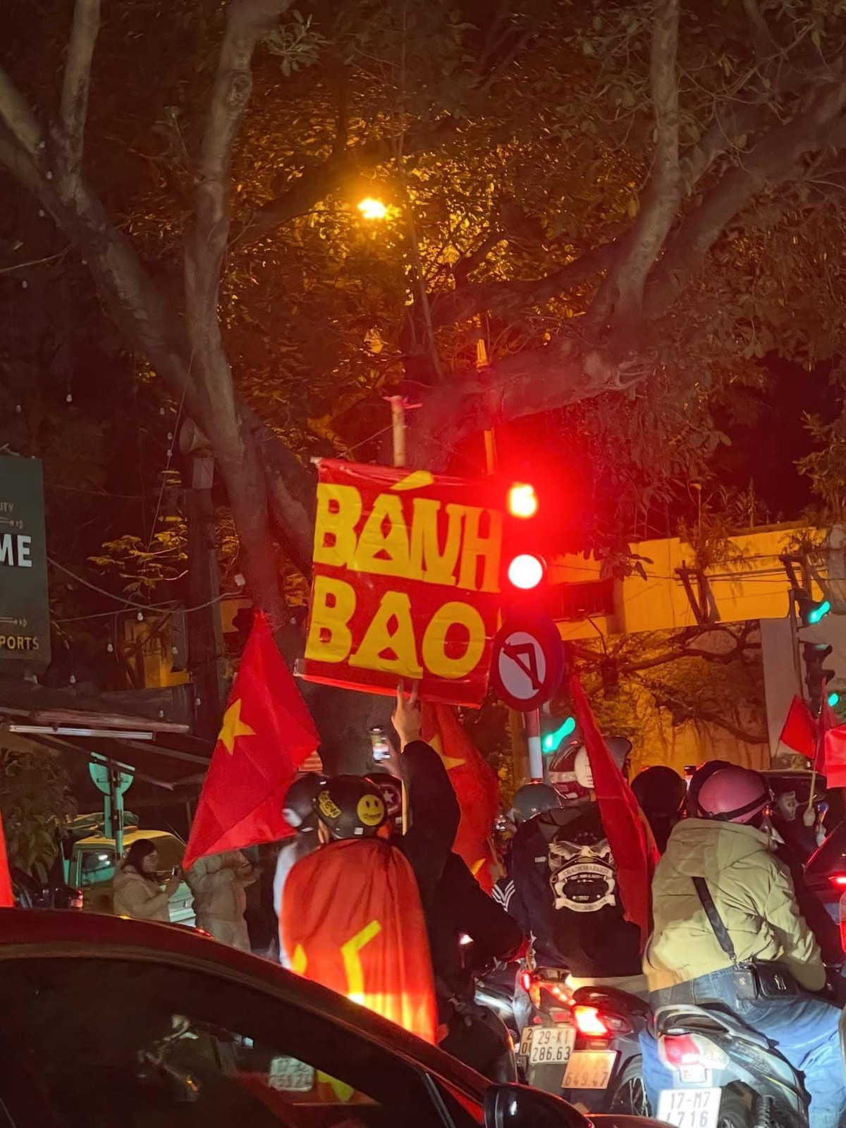 Biển hiệu "BÁNH BAO" rực rỡ dưới ánh đèn đường, chen chúc giữa dòng xe, khiến không khí hội hè thêm phần bình dân và gần gũi.