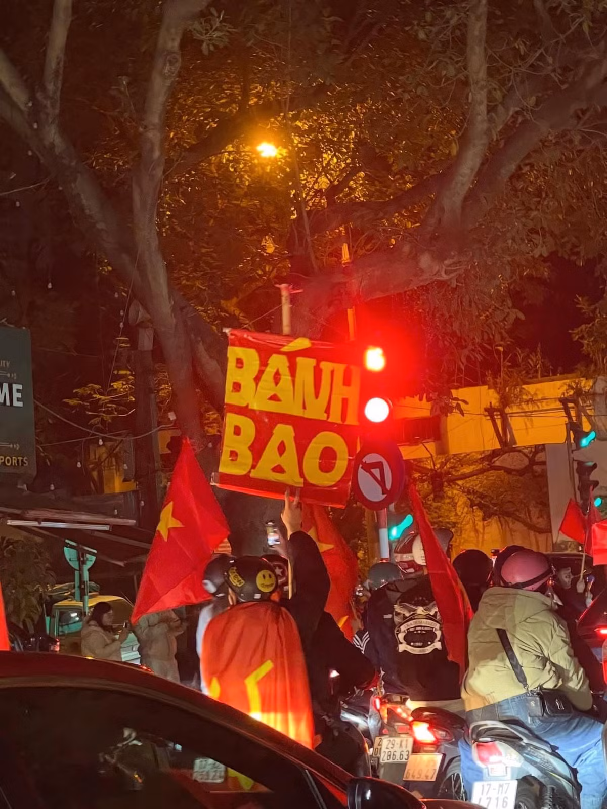 Biển hiệu "BÁNH BAO" rực rỡ dưới ánh đèn đường, chen chúc giữa dòng xe, khiến không khí hội hè thêm phần bình dân và gần gũi.