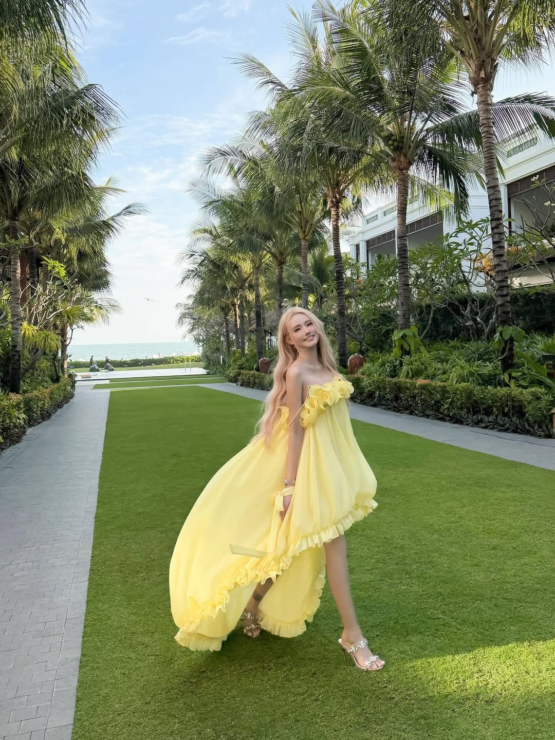 Giữa bối cảnh resort xanh mướt với những hàng dừa trải dài, Jenny Yến tự tin thả dáng đầy chuyên nghiệp. Những khoảnh khắc cô nàng vừa chạy vừa xoay váy mang lại cảm giác phóng khoáng, tràn đầy sức sống. Khi ngồi trên thảm cỏ, cô khéo léo xử lý góc chân để tạo hiệu ứng "hack" chiều cao tối đa, đồng thời nghiêng đầu nhẹ nhàng để bắt trọn ánh sáng mặt trời. (Ảnh: IGNV)