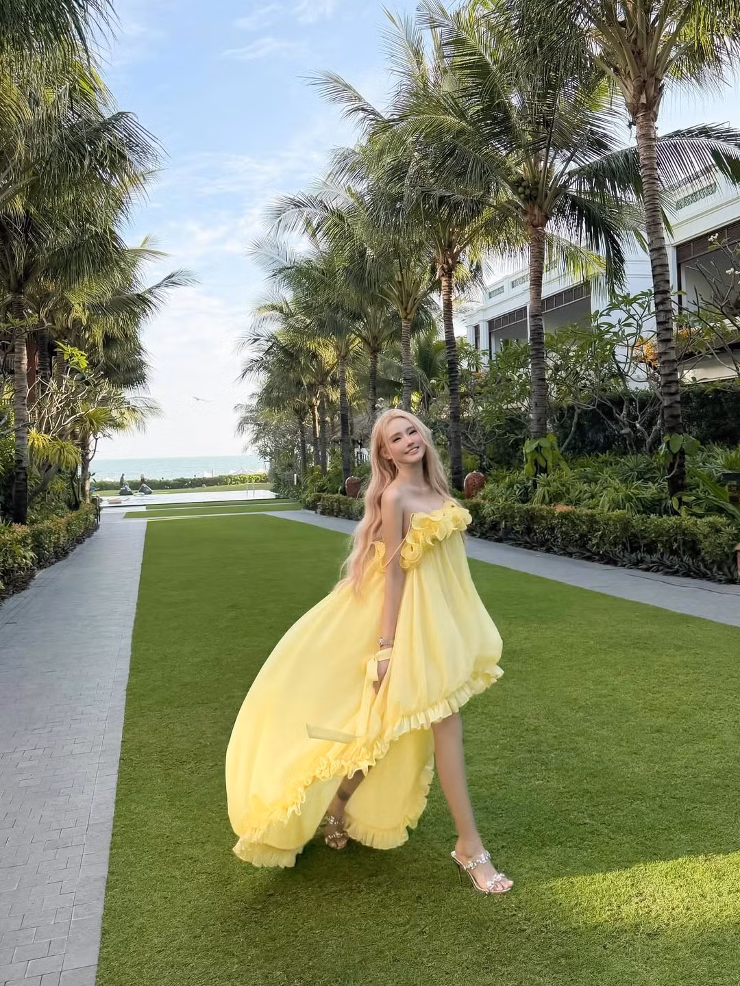 Giữa bối cảnh resort xanh mướt với những hàng dừa trải dài, Jenny Yến tự tin thả dáng đầy chuyên nghiệp. Những khoảnh khắc cô nàng vừa chạy vừa xoay váy mang lại cảm giác phóng khoáng, tràn đầy sức sống. Khi ngồi trên thảm cỏ, cô khéo léo xử lý góc chân để tạo hiệu ứng "hack" chiều cao tối đa, đồng thời nghiêng đầu nhẹ nhàng để bắt trọn ánh sáng mặt trời. (Ảnh: IGNV)