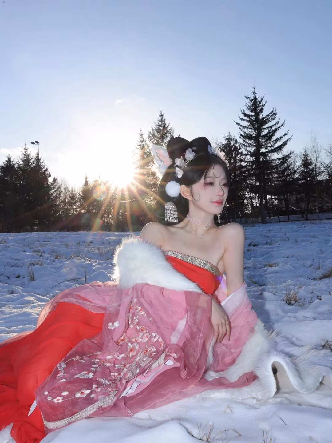 Cô diện một bộ trang phục cổ trang cách điệu, đặc trưng với phần vai trần, làm nổi bật nét quyến rũ và thanh thoát. Hai tông màu chủ đạo là đỏ rực và hồng phấn nhẹ nhàng tạo sự tương phản mạnh mẽ với nền tuyết. (Ảnh: IGNV)