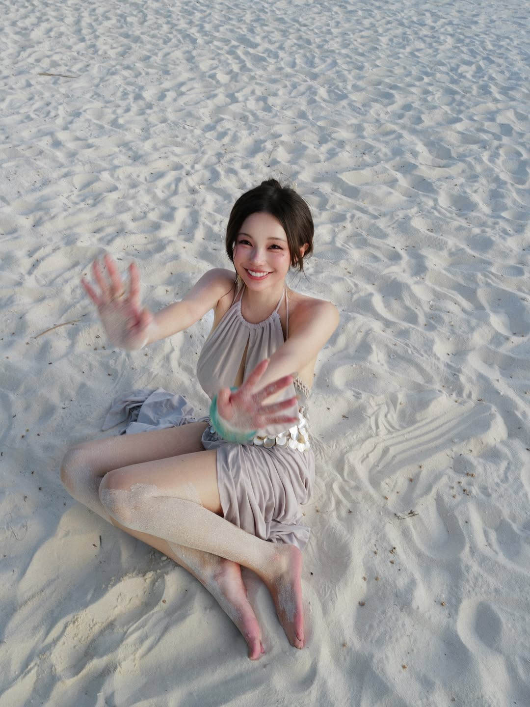 Cô chọn một thiết kế váy màu be nhạt với những đường cắt xẻ táo bạo, điểm xuyết bằng thắt lưng đính vỏ sò lấp lánh, cực kỳ phù hợp với không gian bãi biển. (Ảnh: IGNV)