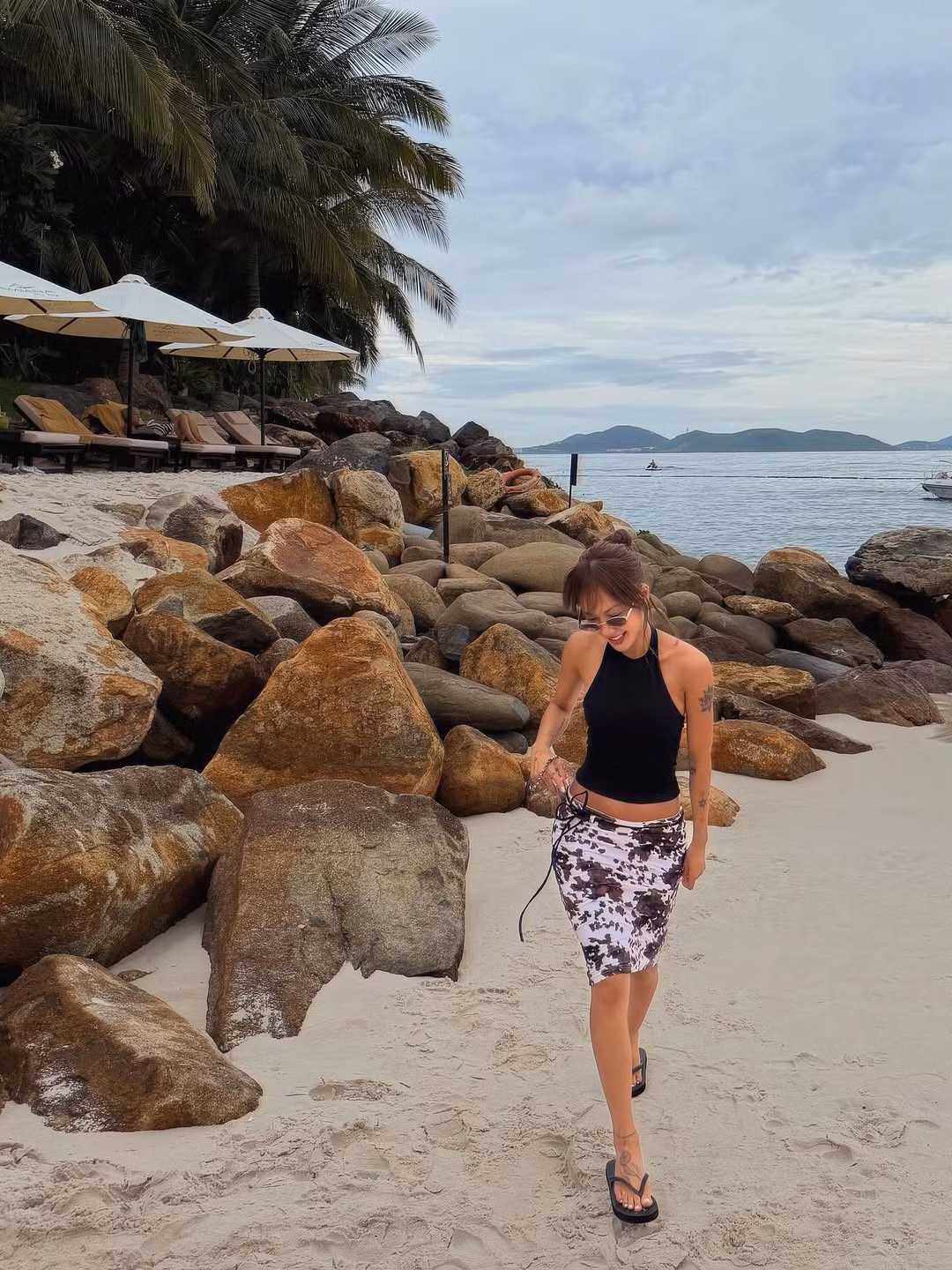 Nữ ca sĩ diện mẫu áo ôm sát đơn giản nhưng cắt xẻ tinh tế với phần cổ yếm màu đen. Thiết kế này không chỉ khoe khéo bờ vai thon thả, hình xăm nghệ thuật trên cánh tay mà còn làm nổi bật vòng eo "con kiến" và vòng bụng săn chắc. (Ảnh: IGNV)