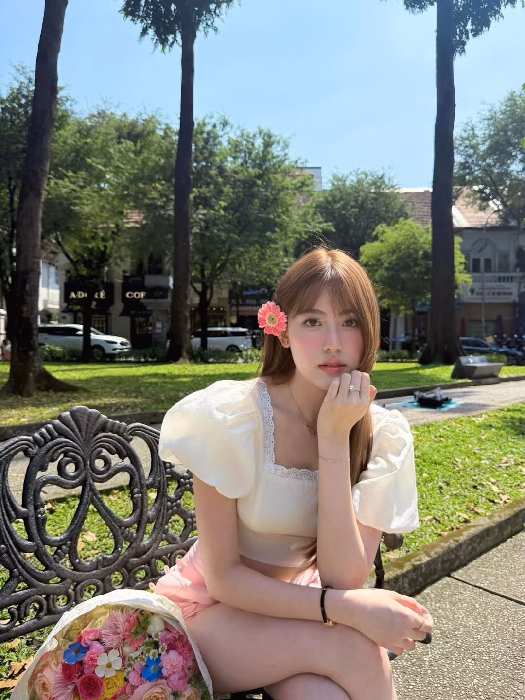 Một cành hoa màu hồng cài nhẹ nhàng bên mái tóc dài óng mượt, cùng bó hoa rực rỡ sắc màu đã giúp cô nàng hóa thân thành "nàng thơ" giữa không gian xanh mát của công viên. (Ảnh: IGNV)