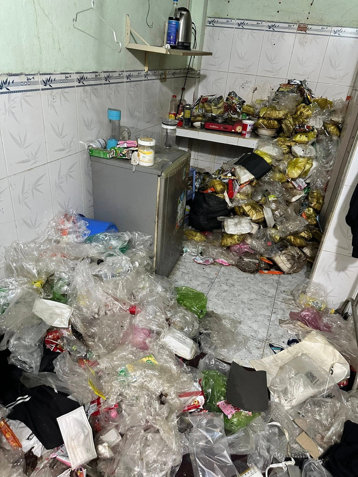 Hàng trăm vỏ hộp cơm, túi nilon đựng thức ăn thừa được tích tụ lâu ngày, chất đống từ sàn nhà lên đến tận kệ bếp.