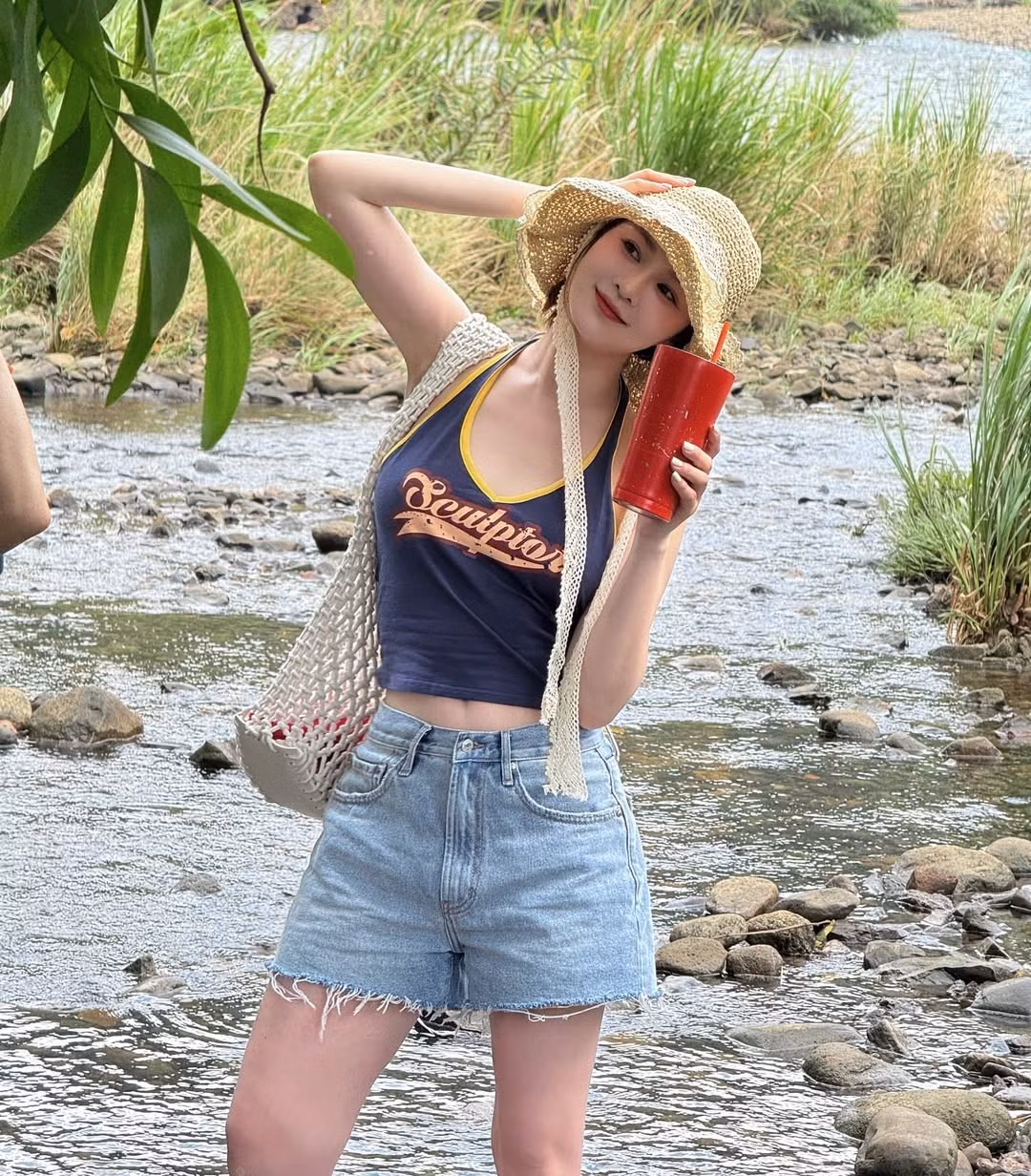 Đôi ủng cao su màu xanh đậm – tưởng chừng đơn điệu – lại là điểm nhấn thú vị, vừa thực tế trong môi trường suối nước, vừa tạo cảm giác “nghệ” rất riêng, chuẩn chất du lịch hè.