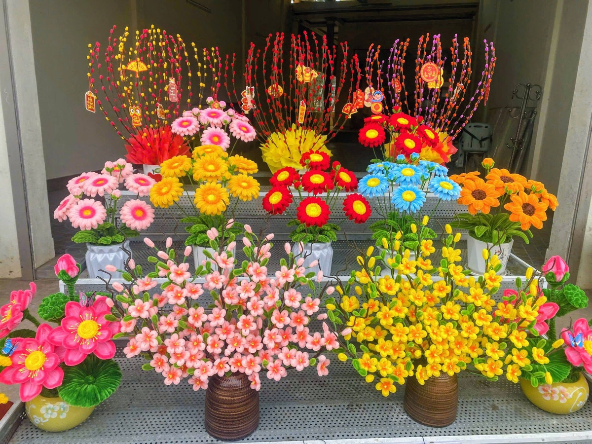 Những bình hoa đào, hoa mai với phần thân được quấn băng keo sáp tạo độ sần sùi như gỗ thật, kết hợp cùng những nụ hoa chúm chím tạo nên vẻ đẹp sống động.