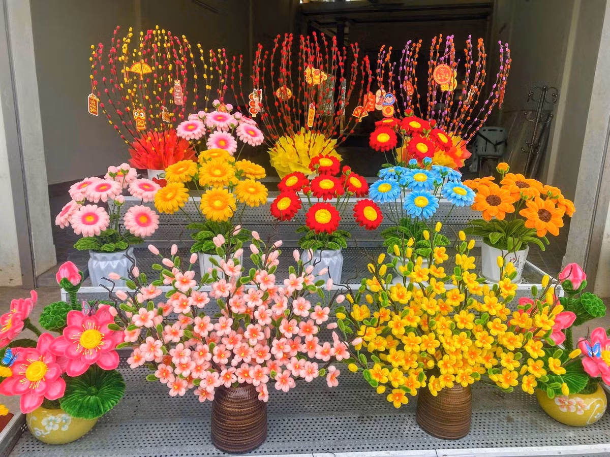 Những bình hoa đào, hoa mai với phần thân được quấn băng keo sáp tạo độ sần sùi như gỗ thật, kết hợp cùng những nụ hoa chúm chím tạo nên vẻ đẹp sống động.