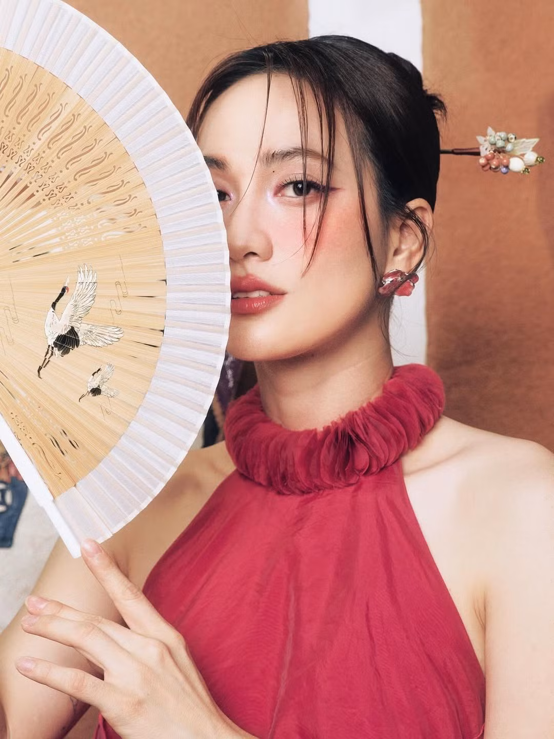 Cô tạo dáng bên cạnh những vật phẩm trang trí như cá chép treo hay đám mây giấy mang màu sắc cổ truyền. Đặc biệt, trong những bức ảnh cận mặt, Phương Anh Đào còn có khoảnh khắc che mặt nửa kín nửa hở, mang lại cảm giác vừa gợi cảm, vừa ma mị.