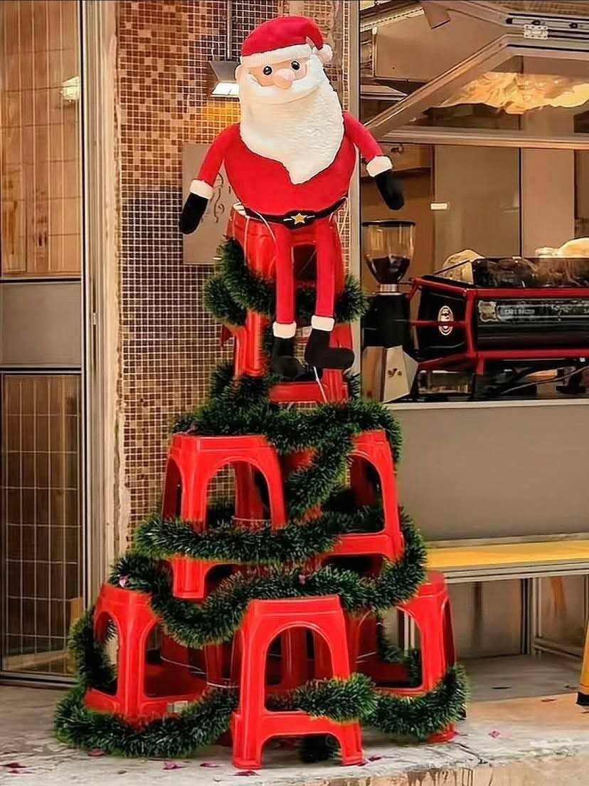 Một chồng ghế nhựa màu đỏ được xếp thành hình chóp, quấn thêm dây kim tuyến xanh và đặt ông già Noel ngồi chễm chệ trên đỉnh. Ý tưởng này vừa đơn giản, vừa hài hước, rất dễ áp dụng ở mọi gia đình hoặc quán cà phê dân giã.