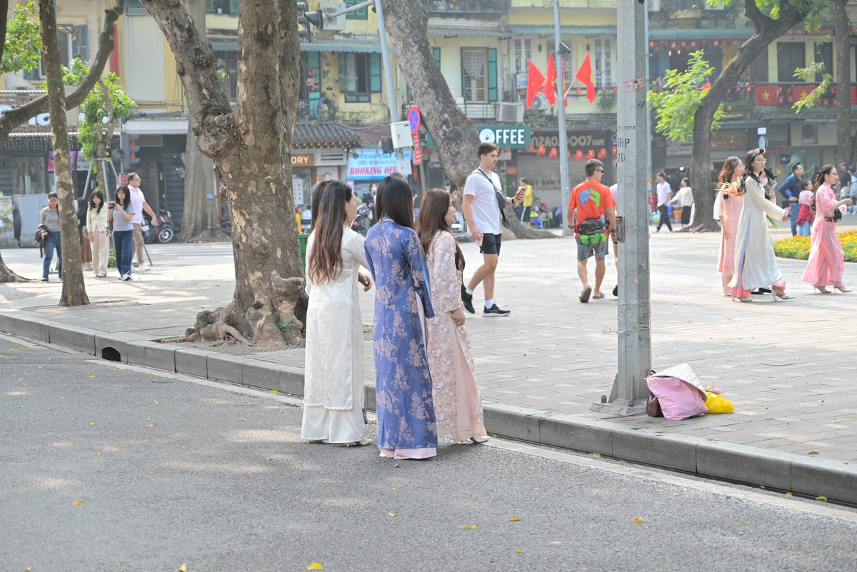 Bên cạnh những nhóm bạn thân, nhiều cặp đôi cũng lựa chọn thời điểm này để lưu giữ những khoảnh khắc ngọt ngào bên nhau. Dưới tán cây xanh mướt, những tà áo dài tung bay trong gió nhẹ tạo nên một bức tranh bình yên, đậm chất Hà thành. (Ảnh trong bài: Vương Lộc/ Hà Nội Riviu)