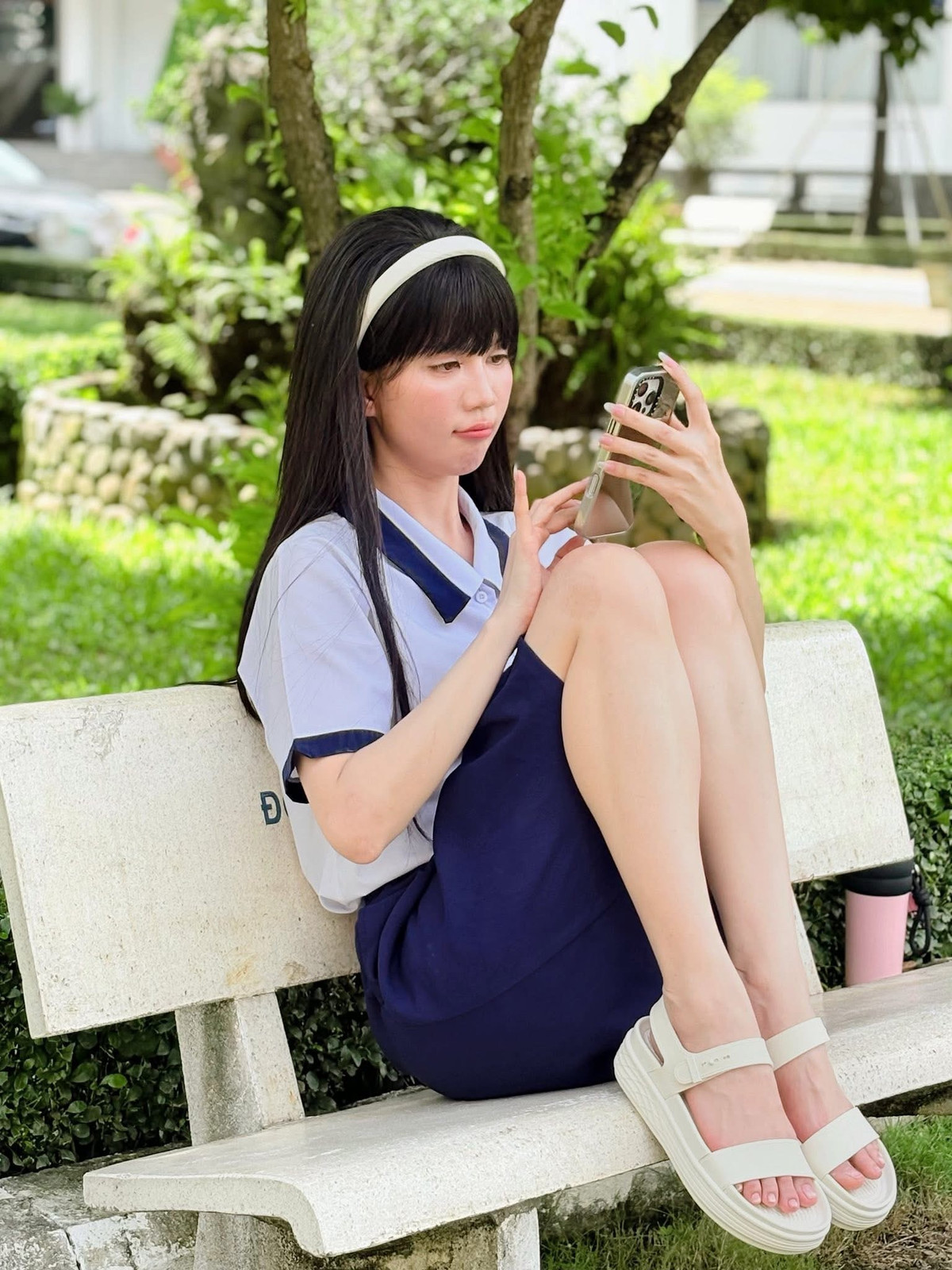 Trong loạt ảnh này, cô khéo léo kết hợp chiếc áo sơ mi trắng đơn giản cùng chân váy xanh than, một combo kinh điển của các cô nữ sinh. Hình ảnh cô ngồi trên ghế đá, e ấp hay đeo cặp, ôm sách vở đã gợi lại bao kỷ niệm thời học trò.