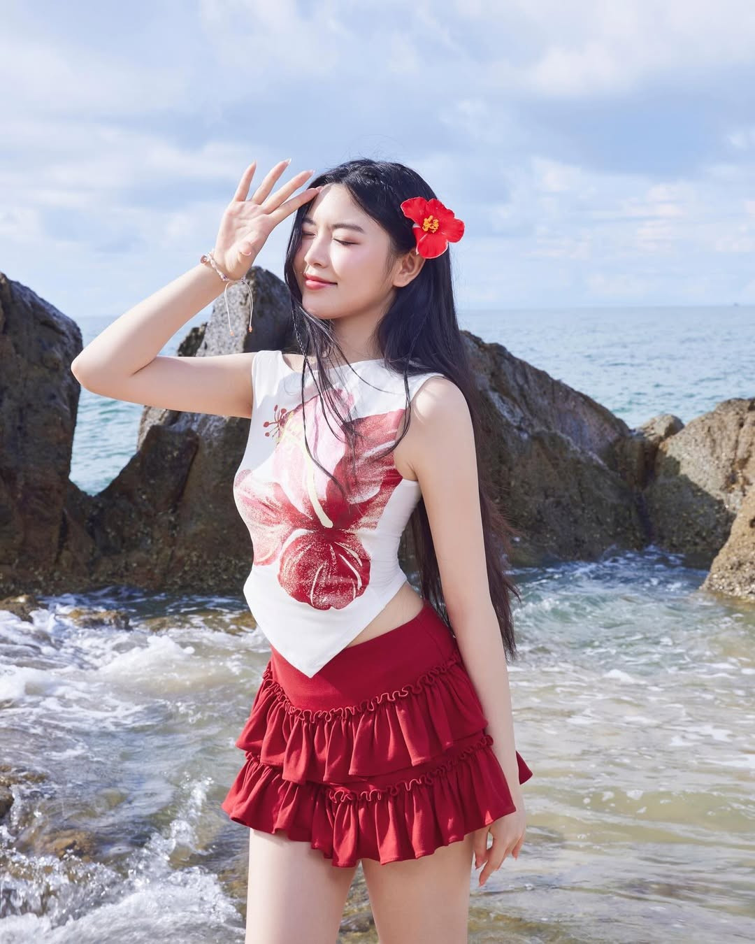 Để hoàn thiện tổng thể, cô nàng không quên cài một bông hoa đỏ trên tóc - chi tiết nhỏ nhưng vô cùng tinh tế, tạo sự hài hòa với tông màu chủ đạo của outfit. Mái tóc dài buông xõa tự nhiên càng làm tôn lên vẻ đẹp trong trẻo của con gái MC nổi tiếng.