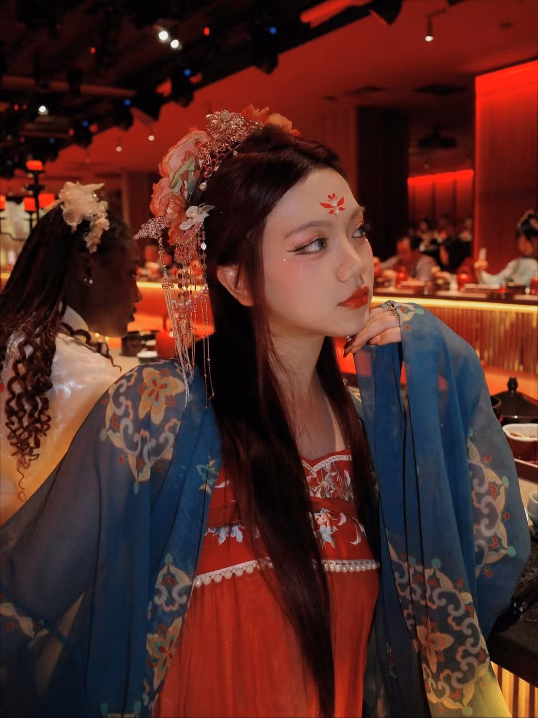 Bảo Hân lựa chọn lối make-up nữ tính nhưng không kém phần sắc sảo. Điểm nhấn là bông hoa điểm trang trên trán màu đỏ rực hình cánh hoa, đôi mắt được kẻ vẽ kỹ lưỡng tạo chiều sâu và đôi môi đỏ cam quyến rũ, tất cả đều theo phong cách trang điểm cổ trang.(Ảnh: IGNV)