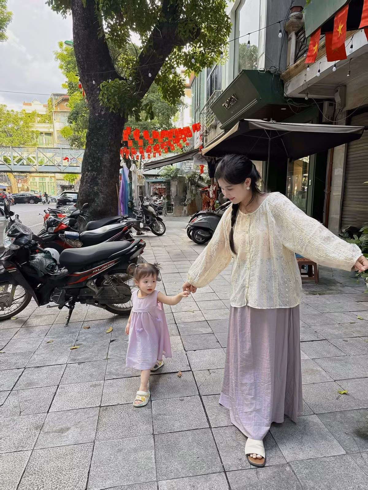 Hình ảnh cô diện áo ren màu kem và chân váy dài màu tím nhạt, tết tóc hai bên, tay trong tay dắt con dạo phố, hay khoảnh khắc âu yếm hôn con cho thấy cuộc sống hạnh phúc, viên mãn của một người mẹ. (Ảnh: IGNV)