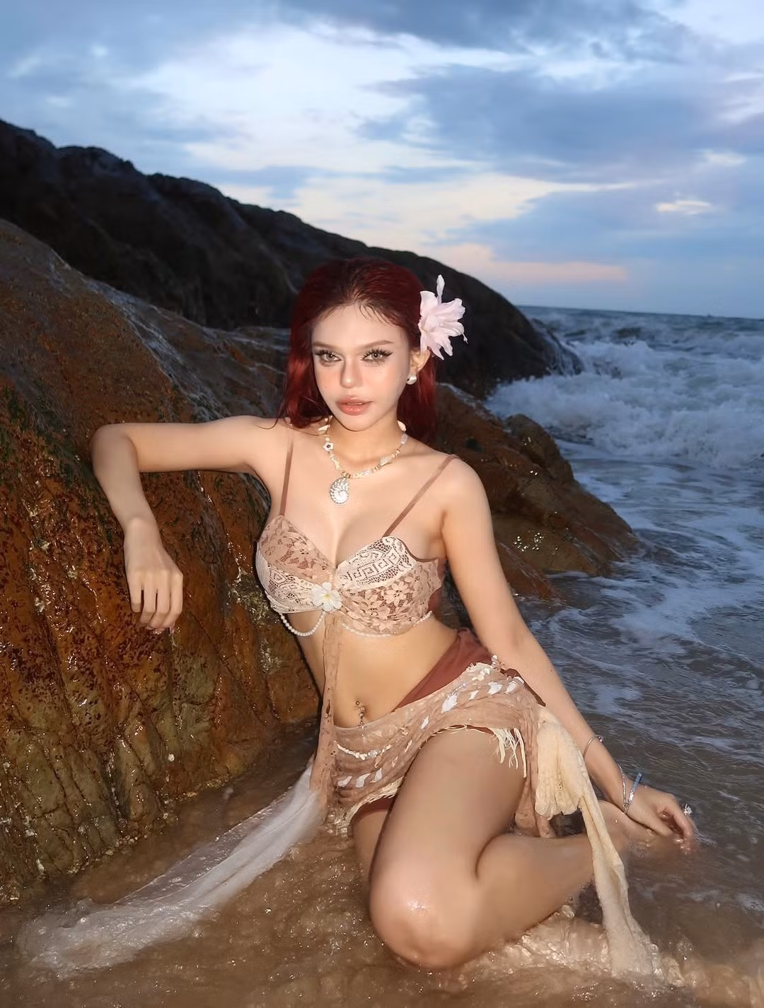 Cô nàng tự tin tạo dáng trên bãi cát, bên cạnh những khối đá và làn sóng biển rì rào. Những pose dáng chuyên nghiệp, từ việc ngồi duyên dáng bên bờ biển cho đến đứng thẳng khoe đường cong cơ thể, đều toát lên sự tự tin và thần thái.