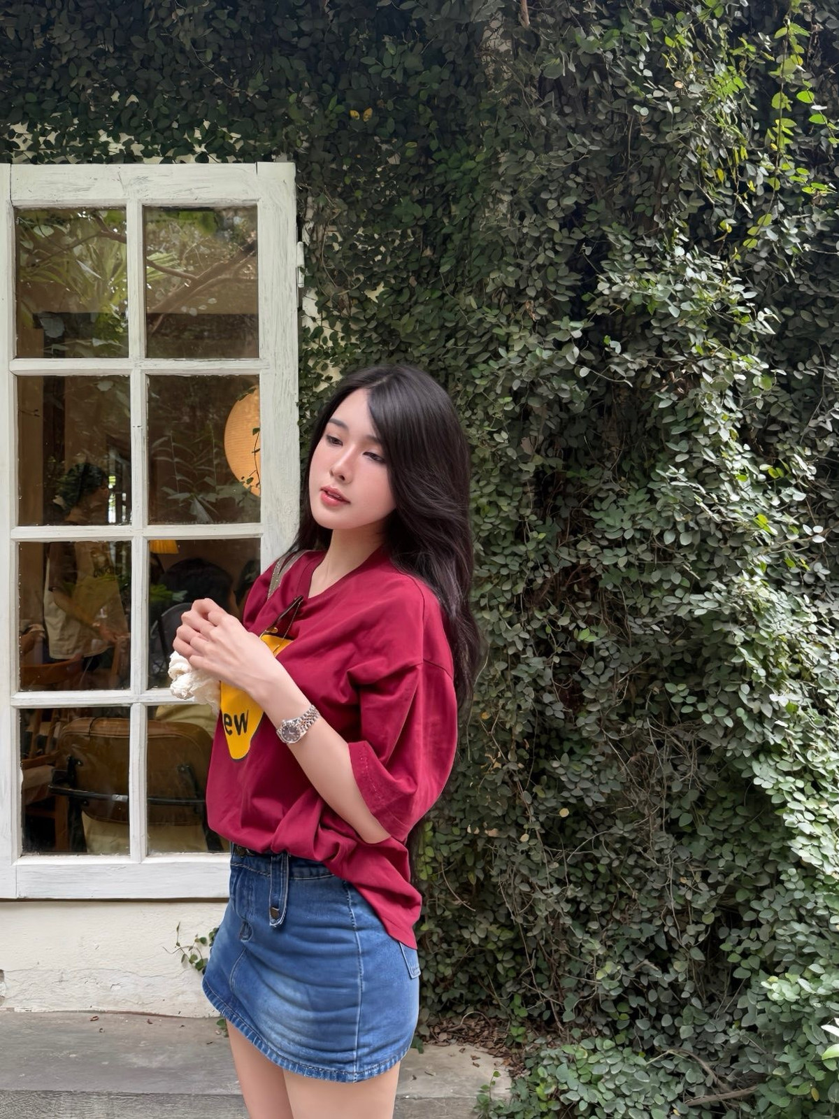 Trong những bức ảnh được chia sẻ, Bích Hạnh chọn cho mình một phong cách đơn giản nhưng cực kỳ "hack dáng" và trendy. Cô nàng diện áo phông oversized màu đỏ đô nổi bật với hình in thương hiệu nổi tiếng, kết hợp cùng chân váy denim chữ A trẻ trung.