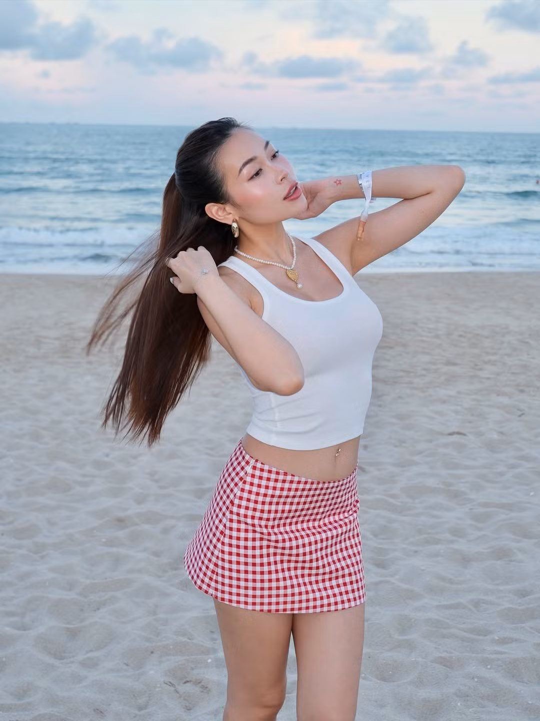 Cô nàng diện một chiếc áo tank top màu trắng ôm sát cơ thể. Chiếc áo đơn giản này không chỉ giúp cô khoe khéo vòng eo thon gọn mà còn mang lại cảm giác thoáng mát, thoải mái tuyệt đối cho các hoạt động ngoài trời.