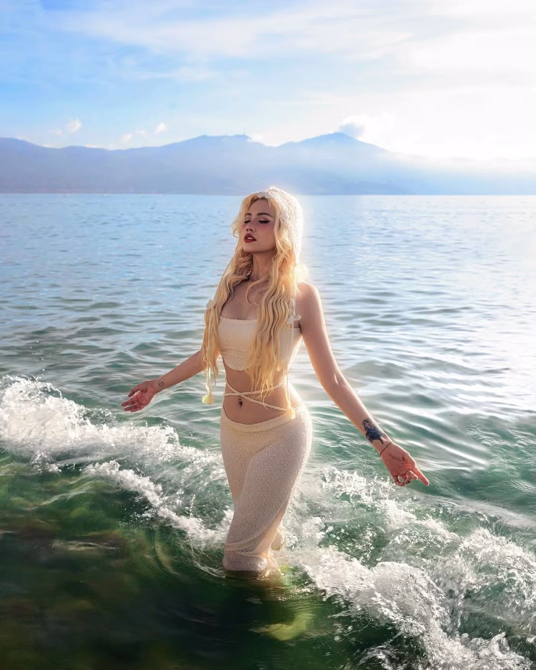 Bộ trang phục của cô nàng cũng được thiết kế đồng điệu với phong cách "nữ thần" với áo quây và quần dài bó sát, cũng được làm từ chất liệu tương tự, ôm sát đường cong cơ thể.