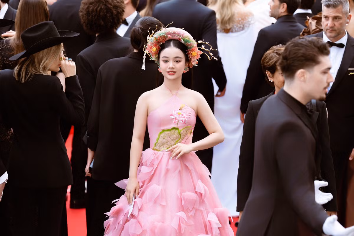 Chiếc yếm màu hồng pastel được thêu tay họa tiết hoa sen mềm mại, kết hợp cùng phần chân váy bồng xếp tầng tạo nên vẻ ngoài vừa ngọt ngào vừa thanh lịch.