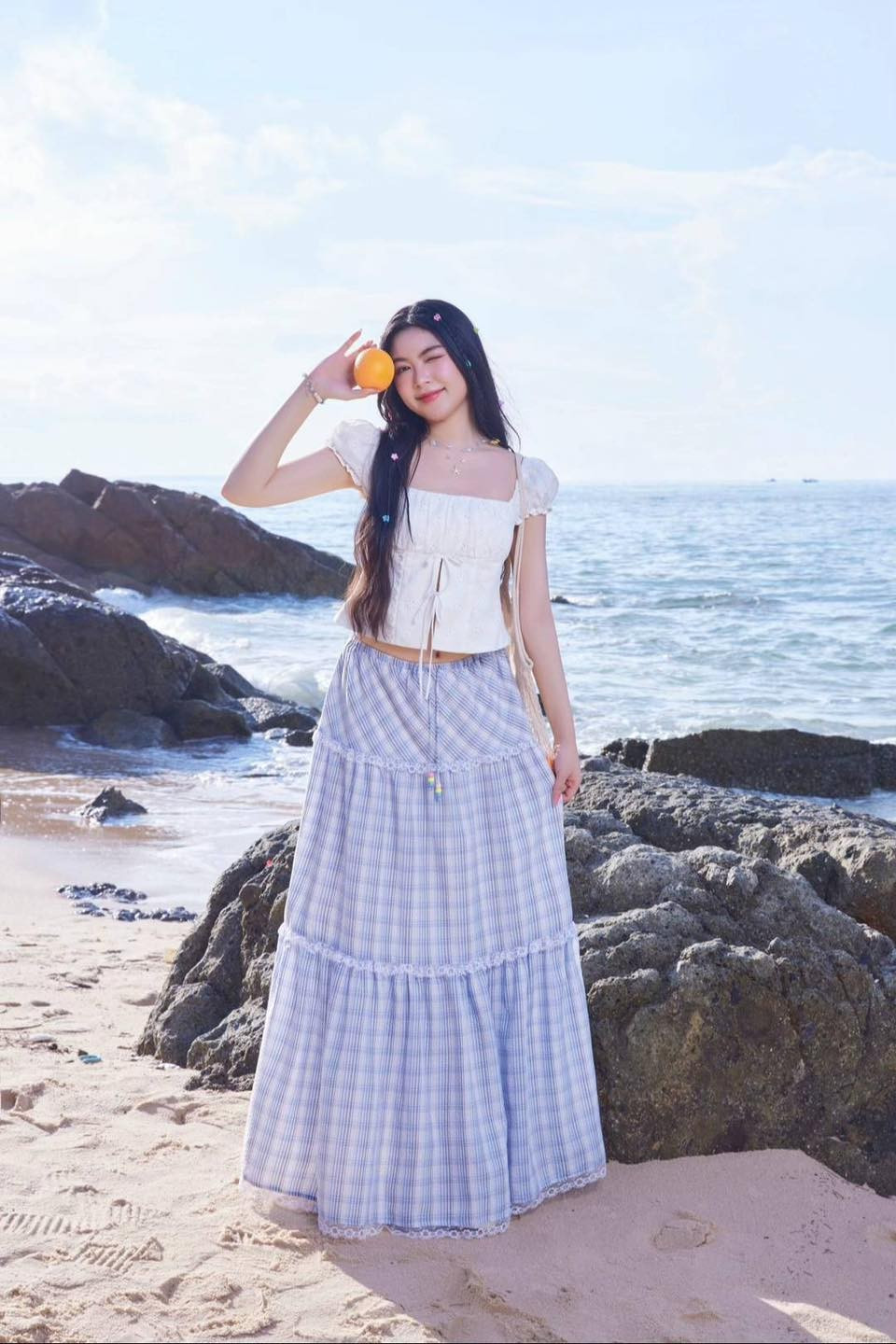 Mái tóc dài thả xõa tự nhiên, đeo vòng cổ ngọc trai nhỏ nhắn tạo điểm nhấn tinh tế. Trong tay vẫn là chiếc túi lưới đựng trái cây - có vẻ như đây đã trở thành "trademark" của Lọ Lem trong loạt ảnh lần này.