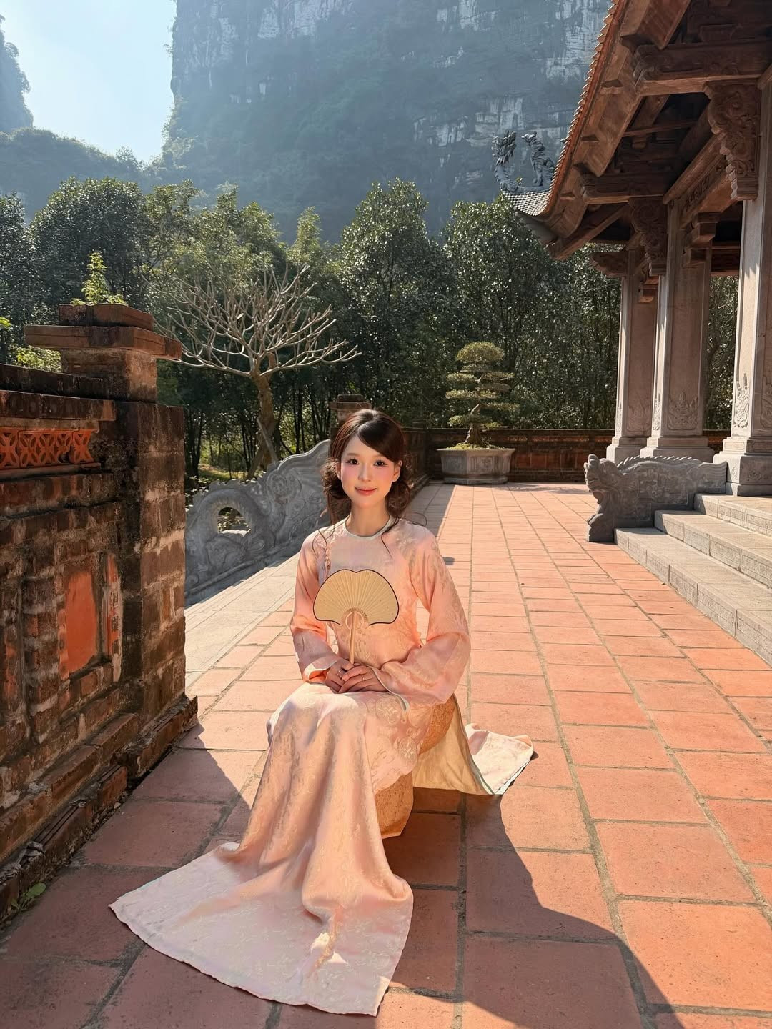 Những mảng tường gạch rêu phong và mái ngói cong vút tạo nên sự tương phản hoàn hảo với tà áo dài sáng màu, khiến bức hình có chiều sâu nghệ thuật hơn. (Ảnh: IGNV)