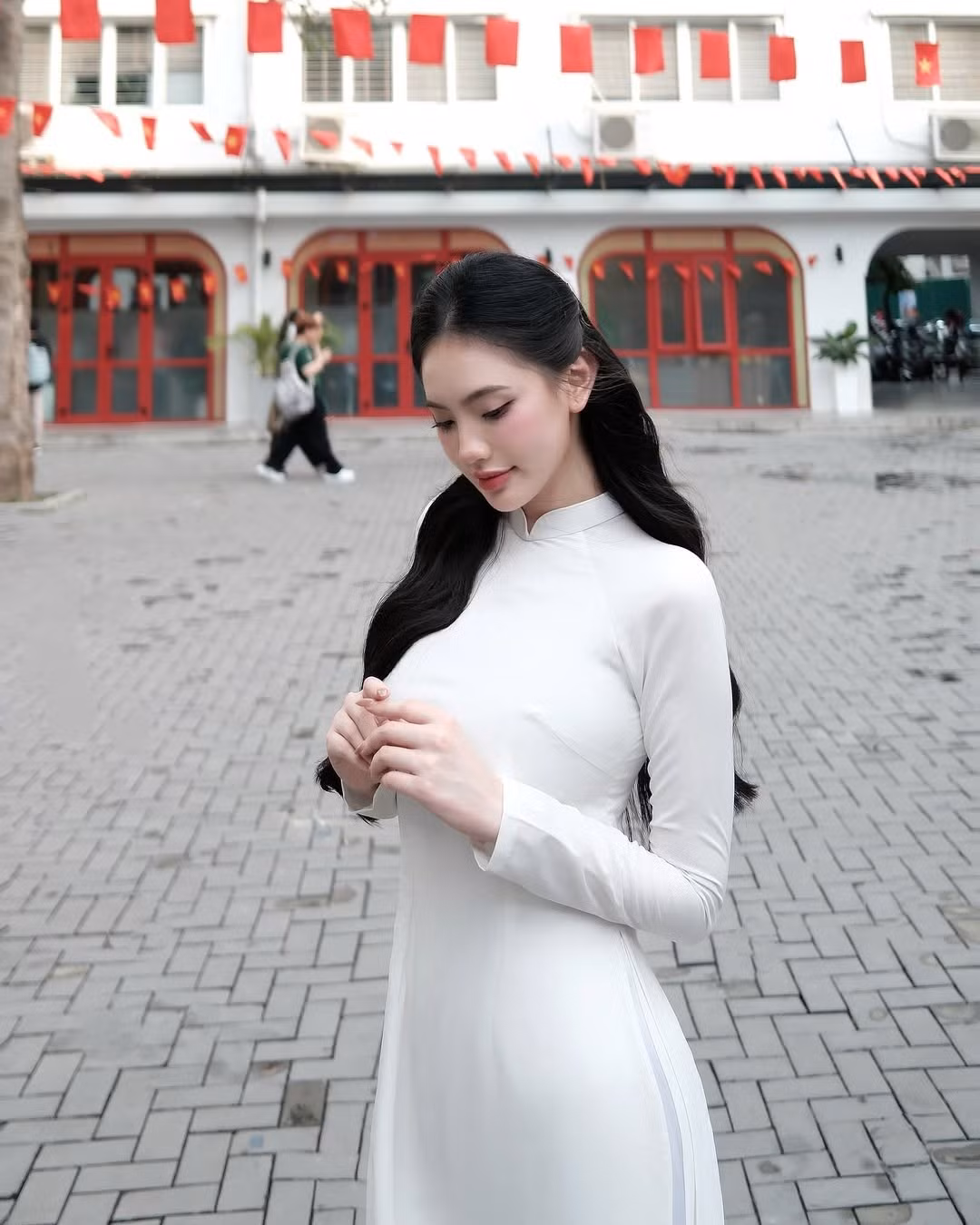 Chiếc áo dài, vốn là biểu tượng của người phụ nữ Việt Nam, càng làm nổi bật vẻ đẹp dịu dàng, e ấp nhưng cũng không kém phần hiện đại của cô gái.