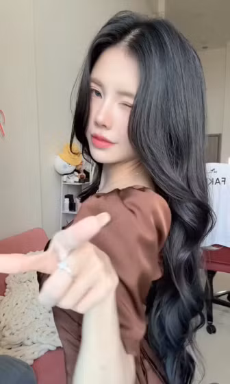 Bên cạnh tâm điểm chính là Mai Dora, các "thánh soi" của cộng đồng Esports còn nhanh chóng phát hiện ra một chi tiết thú vị ở góc phòng. Đó chính là chiếc áo thi đấu có in tên "FAKER" - huyền thoại sống của làng LMHT thế giới - đang được treo ngay phía sau lưng cô. (Ảnh: IGNV)