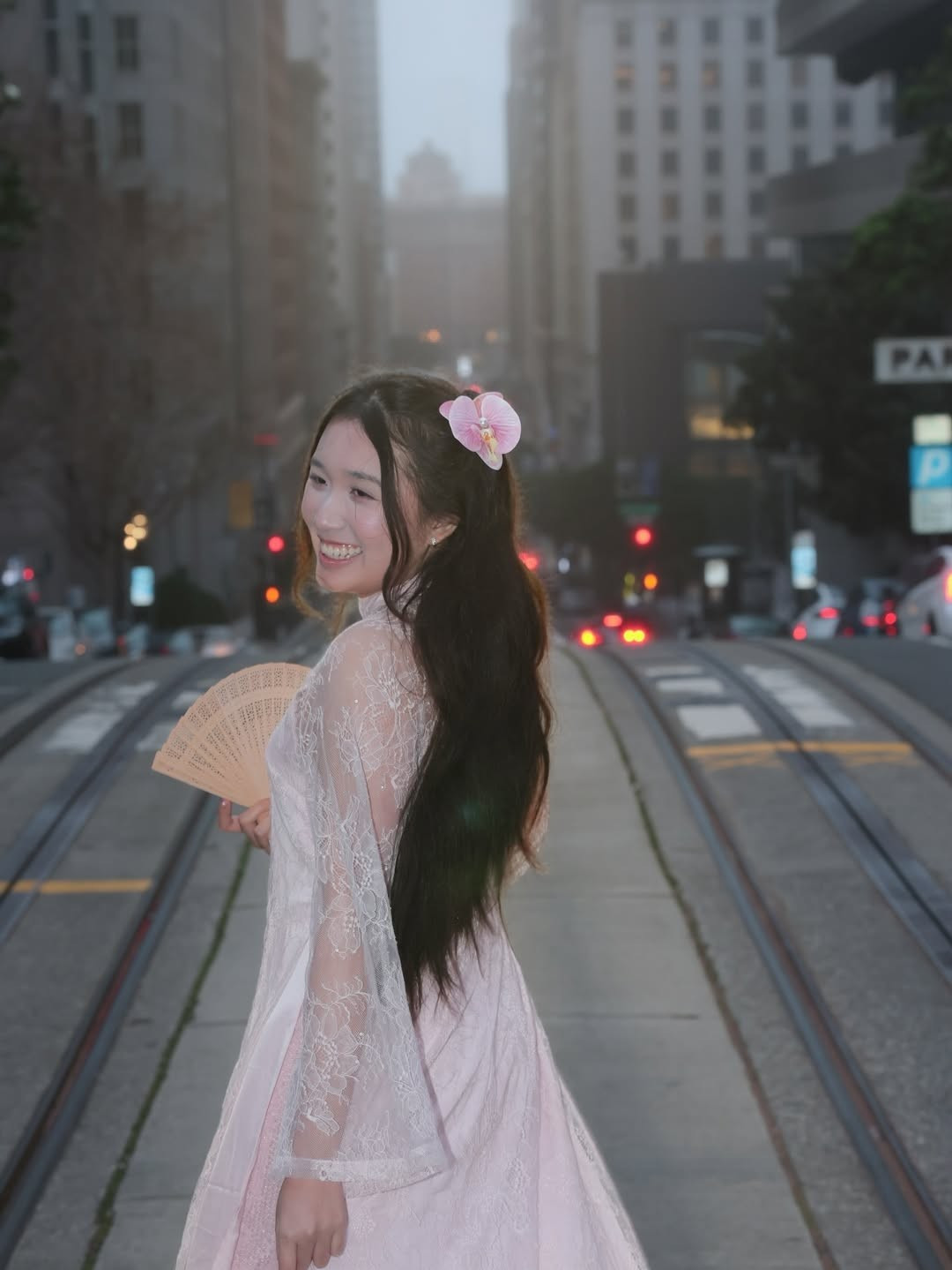 Hình ảnh Jenny đứng giữa những đường ray cáp treo đặc trưng, phía sau là dãy phố cao tầng mờ ảo trong sương mù, tạo nên một chiều sâu nghệ thuật độc đáo. (Ảnh: IGNV)