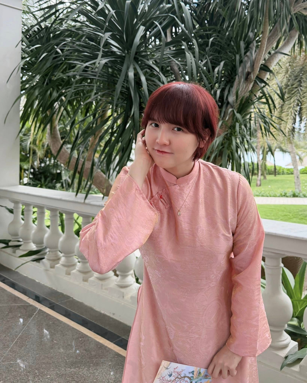 Trong loạt ảnh mới, Hải Tú lựa chọn bộ áo dài tông hồng nhẹ nhàng, kết hợp cùng quần lụa xanh mướt mắt. Sự kết hợp màu sắc này không chỉ mang đậm không khí Tết truyền thống mà còn tôn lên làn da trắng không tì vết của cô. (Ảnh: FBNV)