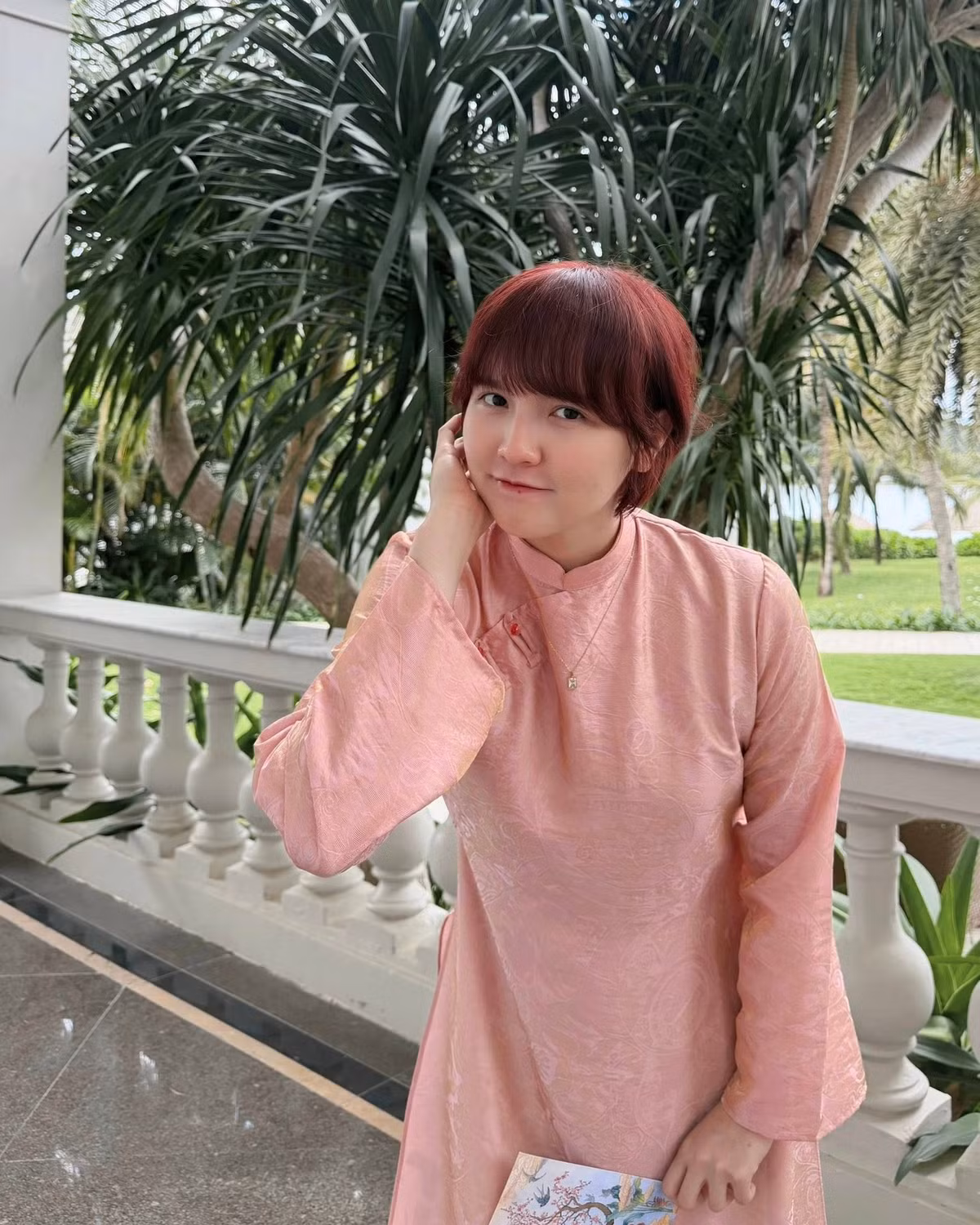 Trong loạt ảnh mới, Hải Tú lựa chọn bộ áo dài tông hồng nhẹ nhàng, kết hợp cùng quần lụa xanh mướt mắt. Sự kết hợp màu sắc này không chỉ mang đậm không khí Tết truyền thống mà còn tôn lên làn da trắng không tì vết của cô. (Ảnh: FBNV)