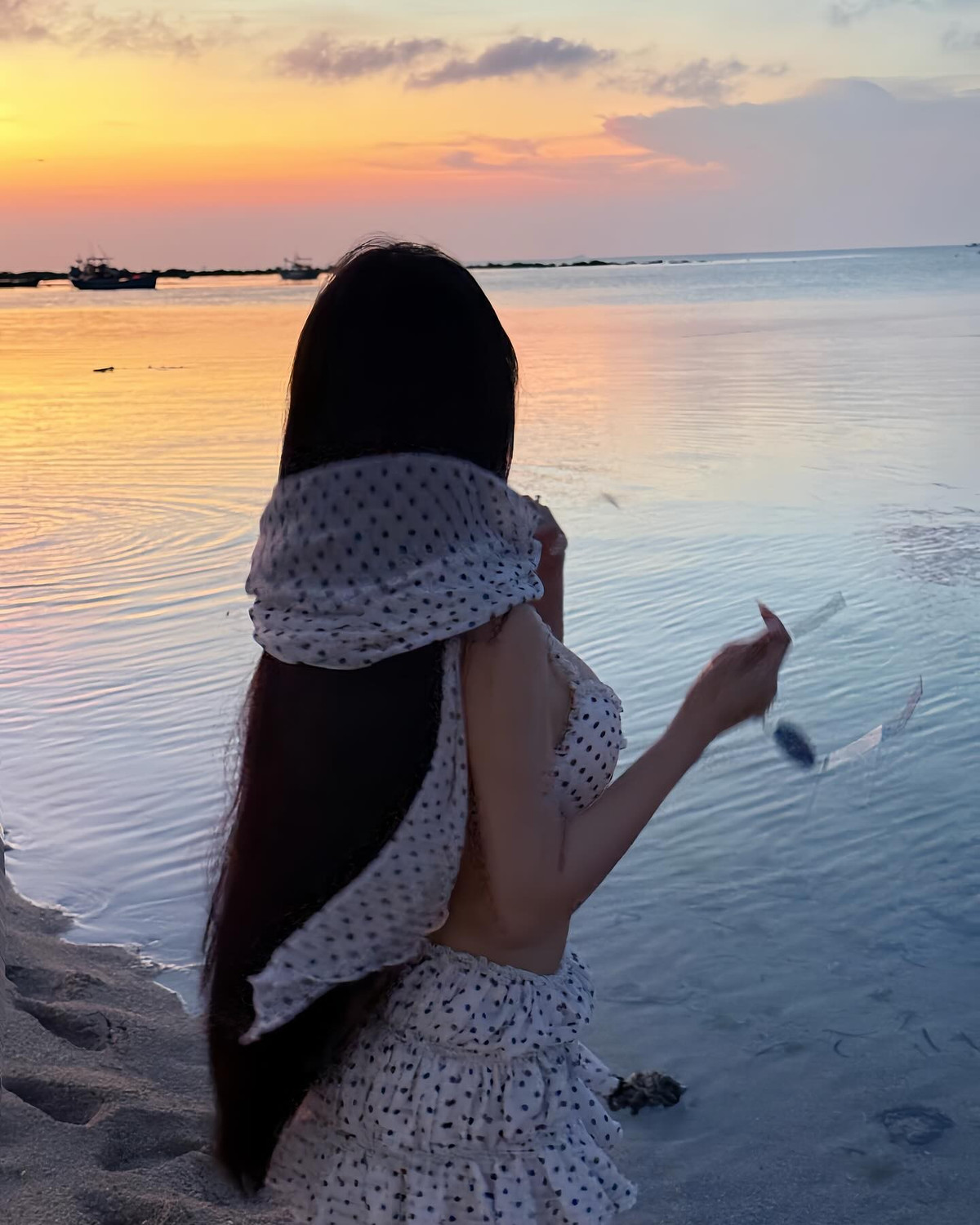 Trong khung cảnh hoàng hôn lãng mạn bên bờ biển, Võ Ngọc Trân diện một bộ bikini hai mảnh kết hợp chân váy bèo cùng khăn trùm đầu vintage, mang đến hình ảnh vừa dịu dàng, vừa quyến rũ.